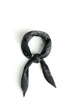 Black bandana with white floral and geometric patterns, folded and tied in a loose knot on a white background.
