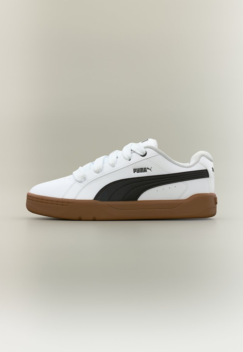 Λευκό αθλητικό παπούτσι Puma με μαύρη πλευρική ρίγα και καφέ σόλα, με λευκά κορδόνια και λογότυπο Puma στη πλευρά, εμφανιζόμενο σε ουδέτερο φόντο.