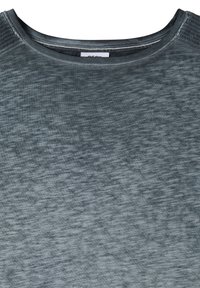 Gros plan sur l'encolure d'un t-shirt en tissu gris texturé avec des coutures visibles et une petite étiquette à l'intérieur du col.