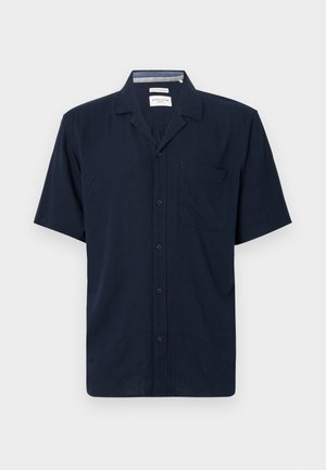 Camisa de mangas curtas em tecido azul marinho escuro, com colarinho, fecho de botões na frente e um único bolso no peito do lado esquerdo.