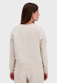Felpa beige chiaro, tessuto morbido, colletto a girocollo, polsini e orlo a coste, progettata con una vestibilità rilassata e minimalizzazione dei dettagli sul retro.