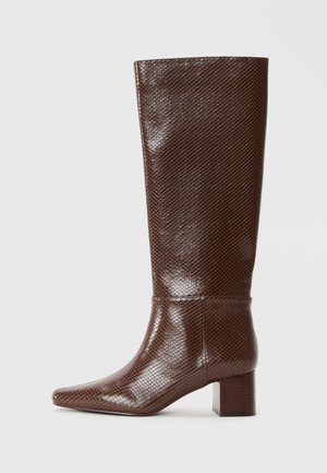 Botte en cuir marron montant jusqu'au genou avec une texture effet peau de serpent, bout pointu et talon bloc sur un fond clair uni.