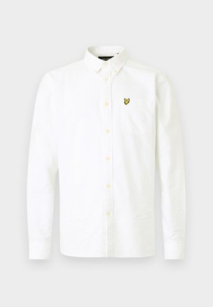 Chemise blanche à manches longues en coton avec un col boutonné, dotée d'une poche poitrine et d'un petit logo jaune sur le côté gauche.