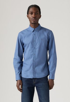 Lichtblauw overhemd met lange mouwen en een puntkraag, voorzien van een subtiel logo, gemaakt van gladde stof, gecombineerd met donkerblauwe jeans.