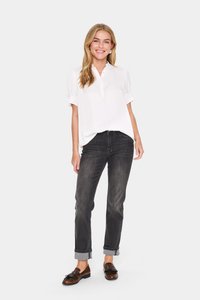 Blusa bianca con bottoni e maniche a sbuffo abbinata a jeans grigio scuro arrotolati e mocassini marroni. La blusa ha un colletto arrotondato e una vestibilità comoda.