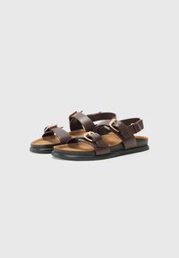 Bruine leren sandalen met een ontwerp van twee banden, een ronde vorm, gouden gespen en een getextureerde bruin voering. Zwarte rubberen zool.