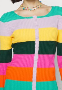 Cárdigan de canalé multicolor con rayas horizontales en verde, rosa, naranja, amarillo y lavanda, con cierre de botones en la parte delantera.