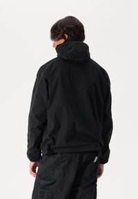 Black waterproof jacket with a hood, featuring contrast stitching and a relaxed fit. Material appears durable with a smooth texture.