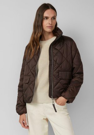 Braune gesteppte Bomberjacke mit hohem Kragen, Reißverschluss und zwei Fronttaschen; getragen über einem cremefarbenen Strickpullover.