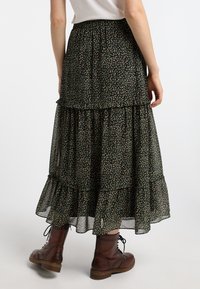 Schwarze Blumen-Maxi-Rock mit geschichteten Rüschen, aus leichtem Stoff. Mit kleinen bunten Blumen und einem gerafften Taillenbund.