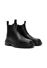Un par de botas Chelsea de cuero negro con paneles laterales elásticos y suelas gruesas de agarre, mostradas sobre un fondo blanco.