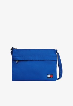 Blåt rektangulært stofetui med lynlås, håndledsrem med mærket "Tommy Jeans" og et lille logo-patch fra Tommy Jeans.