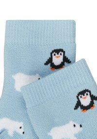 Chaussettes tricotées bleu clair avec des motifs de pingouin et d'ours polaire, ornées d'accents noirs, blancs et orange. Texture douce, design à bord côtes.