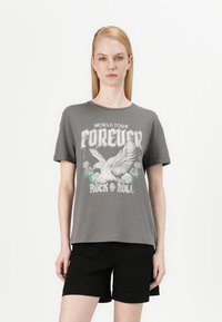 T-shirt grise à manches courtes avec un imprimé graphique représentant un oiseau, des roses et le texte "World Tour Forever Rock & Roll" en accents blancs et verts.