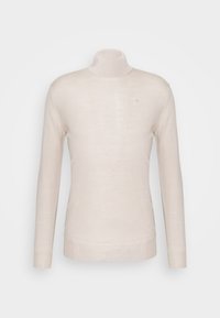 Svetle béžový rolák vyrobený z hladkého úpletového materiálu, s dlouhými rukávy, přiléhavým střihem a nenápadným logem na hrudi.