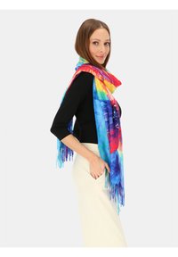 Kolorowy, lekki szalik wykonany z miękkiej tkaniny, zdobiony kwiatowym wzorem w żywych odcieniach niebieskiego, czerwonego, żółtego i zielonego, z frędzlami na krawędziach.