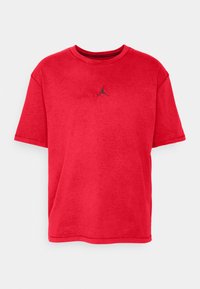 Punainen puuvillapaidan t-paita lyhyillä hihoilla, pyöreällä kauluksella, jossa on pieni musta Jordan-logo rinnassa. Pehmeä rakenne, jossa on hieman haalistunut viimeistely.