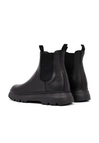 Botas de tobillo de cuero negro con paneles laterales elásticos, acabado texturizado, punta redondeada y suela de goma. Lengüetas para facilitar el uso.