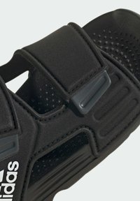 Sorte atletiske sandaler med justerbare remme, struktureret overflade, perforerede detaljer for åndbarhed og robust sål. Har logo.