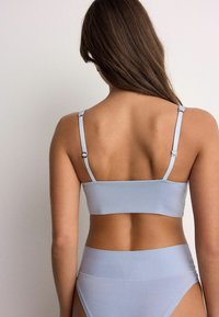 Bralette azzurro chiaro senza cuciture con spalline regolabili, dal design aderente e tessuto liscio. Sono visibili anche mutandine abbinate a vita alta.