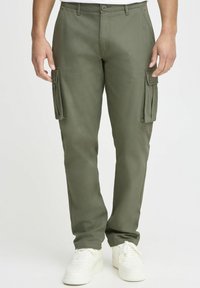 Olivengroene cargobroek met een slim fit, voorzien van zijzakken, een knoopsluiting en lichtgewicht materiaal. Draag het met witte sneakers.