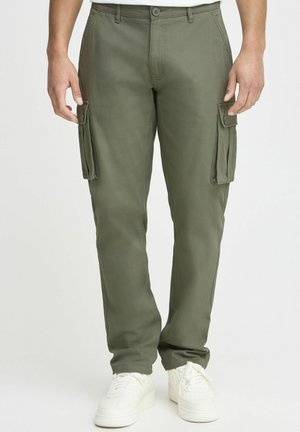 Olivgröna cargobyxor med slim fit, med sidofickor, knappstängning och lätt material. Bärs med vita sneakers.