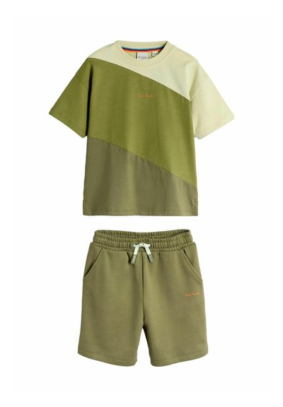 Kortærmet T-shirt med diagonale farveblokke i lys grøn og olivengrøn, kombineret med olivengrønne shorts med snøre i taljen og sidelommer.