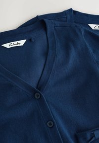 Námornícky modrý sveter vyrobený z jemnej látky, s výstrihom do V, dvomi gombíkmi a štítkom s nápisom "Clarks" na vnútornom golieri.
