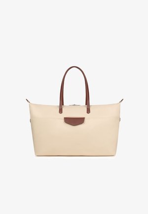Borsa grande color crema con manici in pelle marrone e piccola patta frontale, su sfondo bianco.