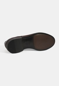 Semelle de chaussure en cuir bordeaux foncé avec une finition lisse, talon en caoutchouc marron contrastant et grip en caoutchouc noir texturé pour une meilleure adhérence.