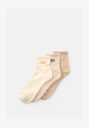 Tre paia di calzini fino alla caviglia in crema, beige e marrone chiaro, ciascuno con un bordo a costine e un piccolo logo vicino alla parte superiore.