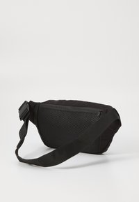Black sling bag with a textured mesh panel, rounded shape, and adjustable strap; features a zippered compartment for secure storage.