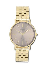 Montre-bracelet en métal doré avec un cadran rond, un cadran brun clair, des index dorés et un bracelet en maille. "OOZOO Vintage" imprimé sur le cadran.