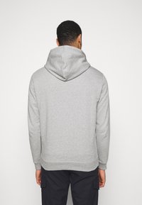 Sudadera gris claro con una capucha amplia, puños y dobladillo acanalados. Diseño sencillo con una textura suave y sin patrones o acentos visibles.