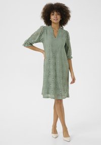 Sage roheline pitskleit V-kaelusega, kolmeveerandi puffvarrukatega ja lillemustritega, millel on põlveni ulatuv lõige ja delikaatne tekstuur.