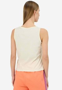 Top senza maniche di un giallo chiaro con scollatura rotonda. Materiale in cotone morbido. Design semplice, senza modelli o dettagli visibili.