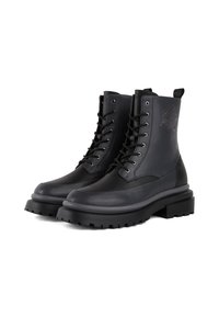 Botines de cuero negro con cordones, suela de goma gruesa y un logo decorativo en el lateral. Textura suave y diseño robusto.