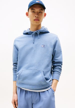 Felpa leggera blu con cappuccio regolabile, tasca frontale e piccolo logo. Tessuto comodo con polsini a coste, abbinata a pantaloni leggeri blu dello stesso tono.