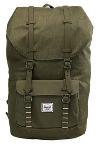 Zielona oliwkowa torba na plecy z klapą, regulowanymi ramiączkami, przednią kieszenią i wyraźną łatą z logo. Teksturowana powierzchnia i solidne okucia.