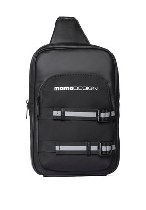 Sac bandoulière rectangulaire noir avec logo blanc "Momo Design", poche zippée à l'avant et deux sangles réglables noires et grises à rayures avec boucles.