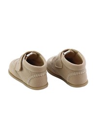 Zapatos de bebé beige hechos de cuero texturizado con una correa de velcro, forma redondeada y costuras en contraste a lo largo de las costuras.