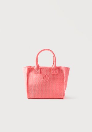 Borsa intrecciata rosa con due manici e un emblema floreale circolare sulla parte anteriore, su uno sfondo bianco semplice.