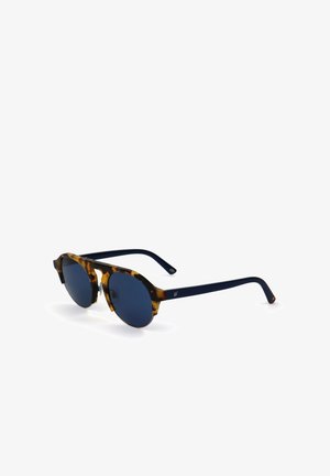 Occhiali da sole con montatura in tartaruga e lenti rotonde di colore blu scuro, con aste solide blu scuro, mostrati leggermente inclinati su sfondo bianco.