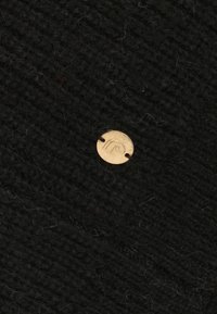 Zwarte gebreide stof met een gestructureerd patroon; voorzien van een kleine gouden knop met een logo, wat detail en contrast toevoegt.