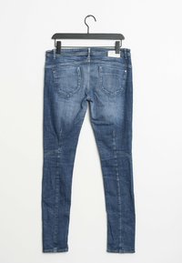 Džíny skinny střihu z tmavě modrého denimu s hladkou texturou, pětipočítačovým designem a výraznými švy na zadní straně a nohavicích.