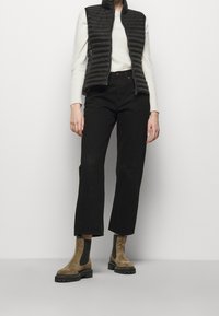 Svart quiltad väst, vit tröja, svarta högmidjade byxor och taupe mocka anklarstövlar med svarta sulor. En enkel, funktionell outfit.