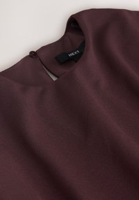 Dark burgundy satin blouse with keyhole back and button closure, showing neckline and fabric texture.