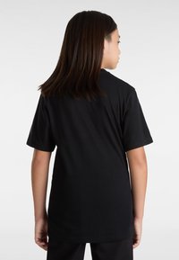 Camiseta negra de manga corta con un ajuste holgado, cuello redondo y tela de algodón suave. La vista trasera muestra una textura lisa y un diseño simple.