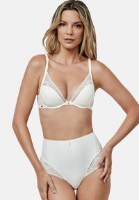 Soutien-gorge blanc avec des accents en dentelle et des bretelles ajustables, assorti à une culotte blanche taille haute présentant des détails en dentelle similaires sur les côtés.