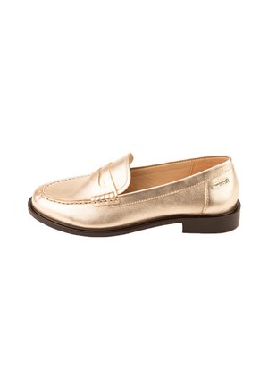 Mocassino in pelle dorata con punta arrotondata, suola piana marrone e dettagli cuciti sulla parte superiore. Presenta una piccola patta decorativa.